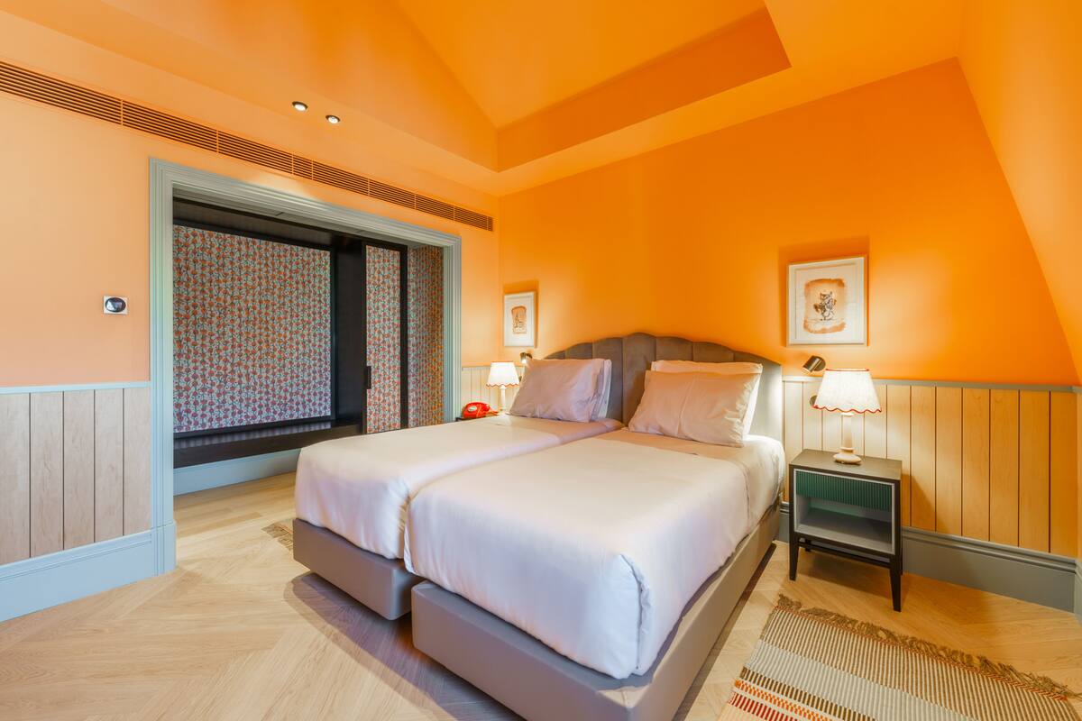 Un dormitorio con una cama grande, dos mesitas de noche y una ventana con cortinas estampadas.