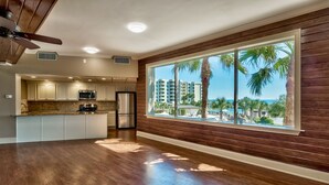 Een moderne keuken met een groot raam met uitzicht op een strand en palmbomen.