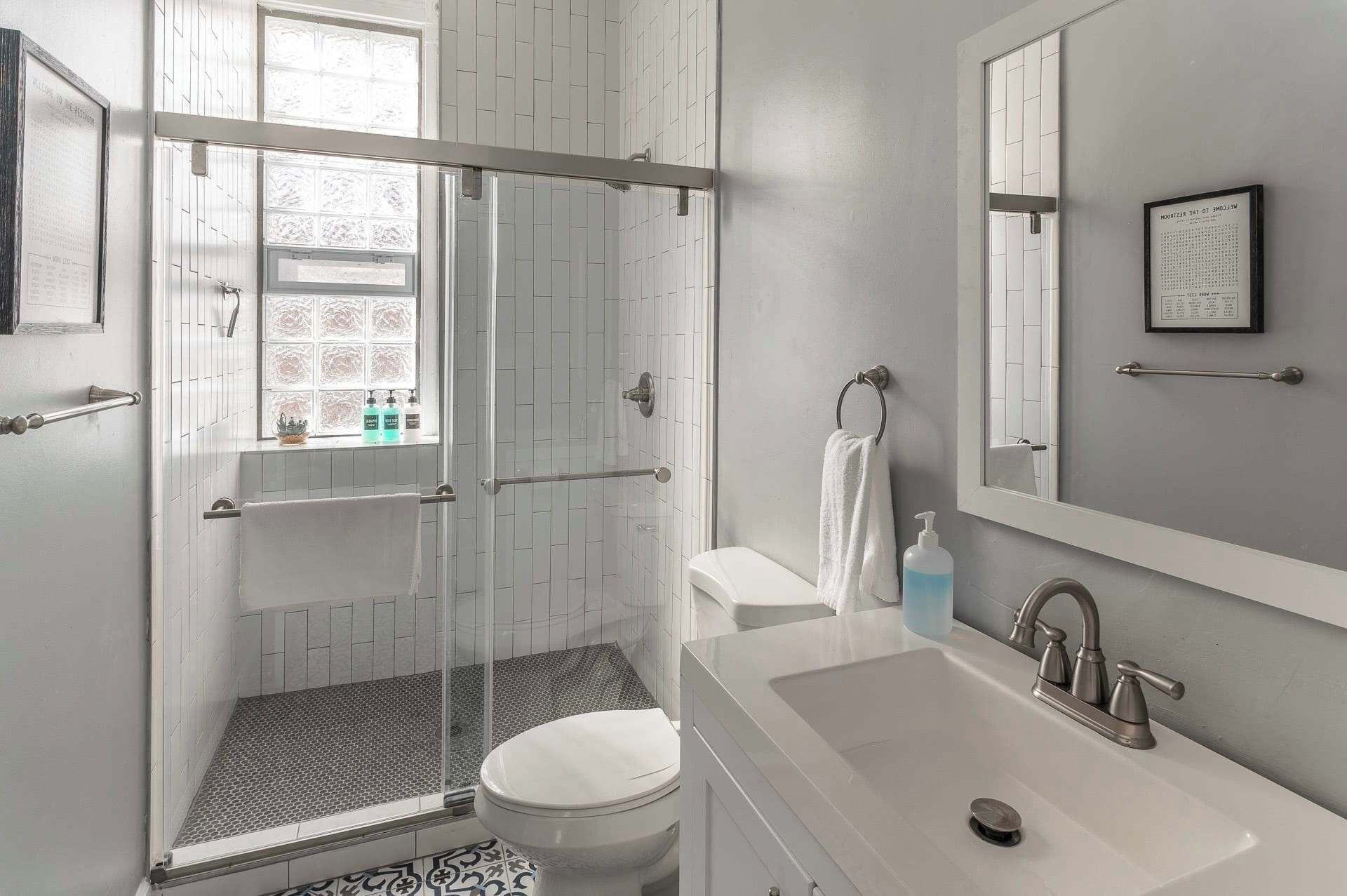 Ein modernes Badezimmer mit Dusche, Toilette, Waschbecken und einem großen Spiegel.