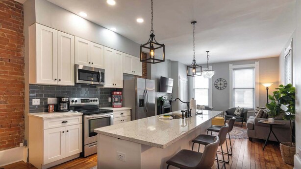 A modern kitchen with white cabinets, stainless steel appliances, and a central island with bar stools.