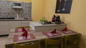 Un coin repas avec une table dressée pour quatre personnes, un four à micro-ondes et un petit espace cuisine.