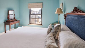 Ein Schlafzimmer mit einem großen Bett, einem Fenster mit Blick, einem Nachttisch und einer Lampe.