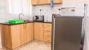 Une cuisine avec des meubles de rangement en bois, un plan de travail noir, un four à micro-ondes, un grille-pain et un réfrigérateur.