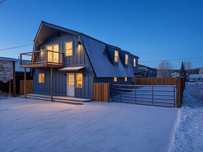 Une maison à deux étages avec un balcon, un garage et une cour clôturée.