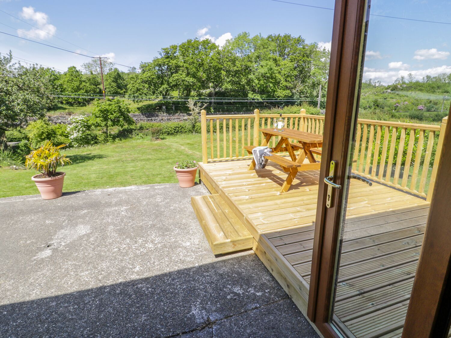 Una terraza de madera con una mesa de picnic y plantas en macetas.