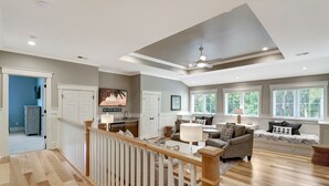 A spacious living area with a high ceiling, a staircase, and a view of the outdoors through large windows. - Brand New Construction 3rd Row Home in Palmetto Dunes! (Hilton Head Island)