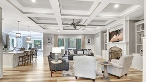 A spacious living room with a fireplace, a ceiling fan, and a large TV. - Brand New Construction 3rd Row Home in Palmetto Dunes! (Hilton Head Island)