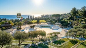 Un’area curata con una piscina circolare, palme e vista sul mare.