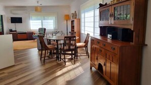 Une cuisine moderne avec des meubles en bois, une table à manger avec des chaises et une grande fenêtre qui laisse entrer la lumière naturelle.