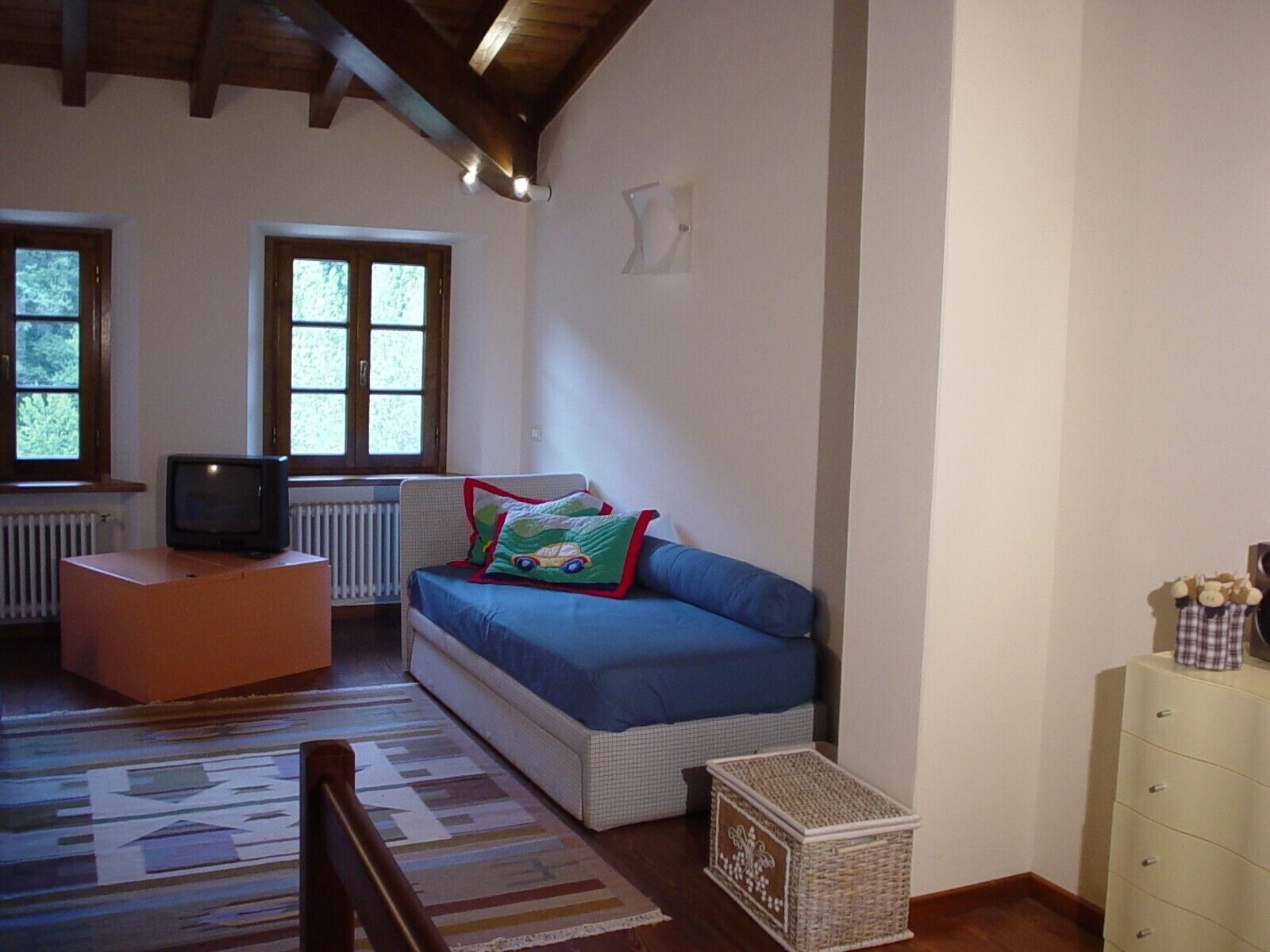 A cozy living room with a sofa, a television, and a radiator.