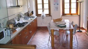 Une cuisine avec des meubles de rangement en bois, une cuisinière et une table à manger avec des chaises.