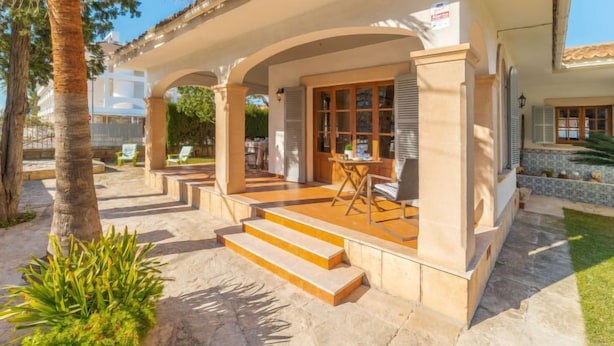 A covered outdoor area with steps leading to a patio, palm trees, and a tiled floor. - Can Xiroia by Interhome (Port d'Alcúdia)