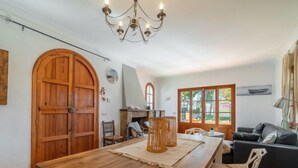 A dining area with a wooden table, chairs, a chandelier, and a view of the outdoors through a window. - Can Xiroia by Interhome (Port d'Alcúdia)