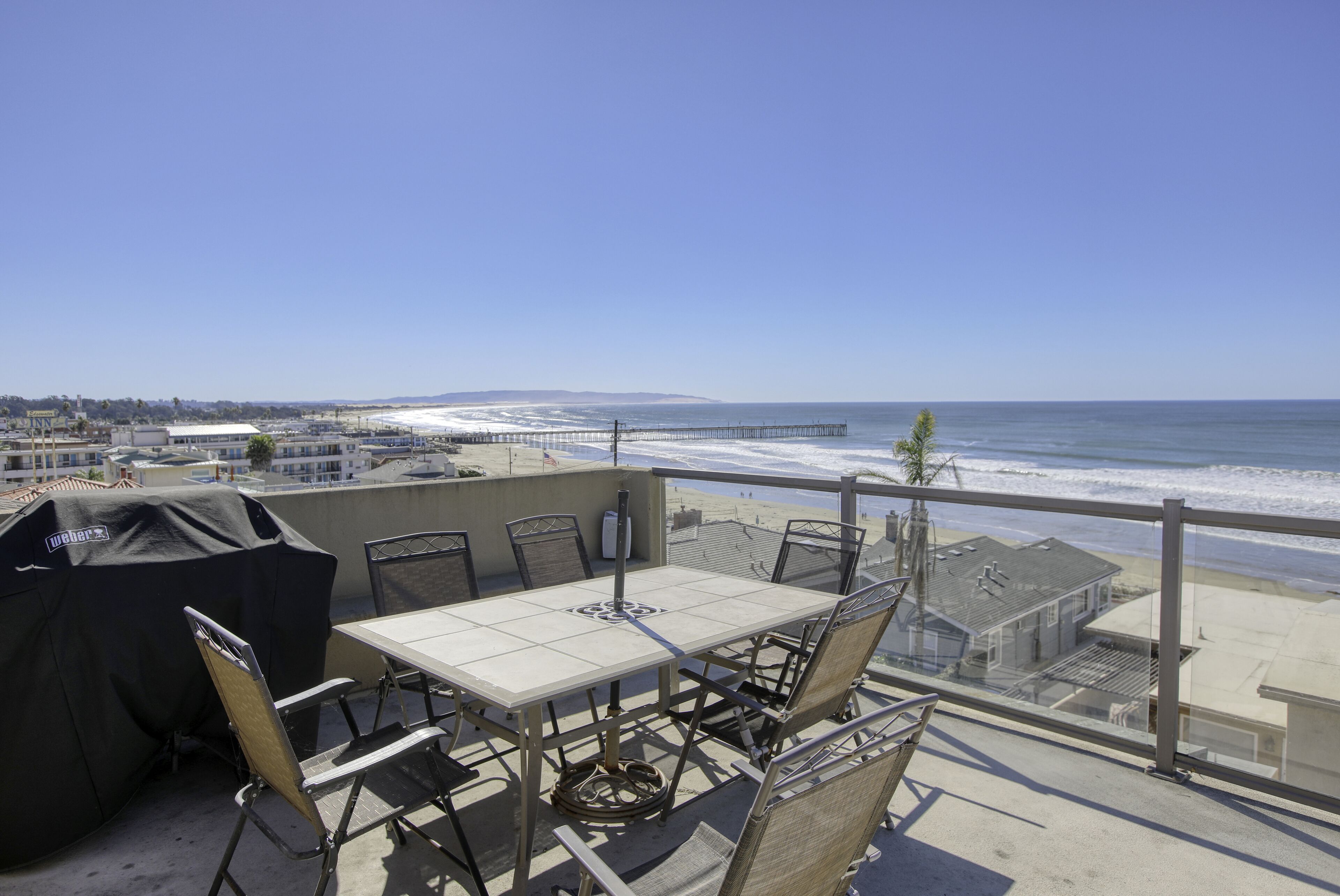 Un balcon avec une table et des chaises donnant sur une plage et l’océan.