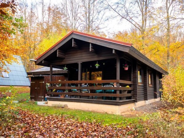 Eine Holzhütte mit Veranda, Sitzgelegenheiten und einer kleinen Deckterrasse.