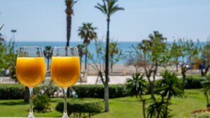 Two glasses of orange juice on a balcony with a view of the beach and palm trees. - Apartment (Torremolinos)