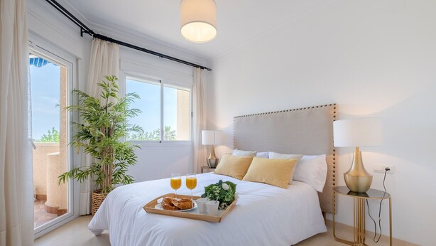A hotel room with a bed, bedside lamps, a tray with croissants and juice, and a potted plant. - Apartment (Torremolinos)