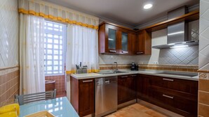 A modern kitchen with wooden cabinets, a stainless steel dishwasher, and a tiled backsplash. - Apartment (Torremolinos)