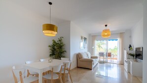 A modern living room with a white sofa, a dining table with chairs, and two pendant lights. - Apartment (Torremolinos)