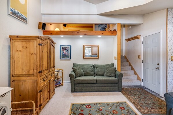 Cozy living area with a high ceiling, sofa, and staircase.