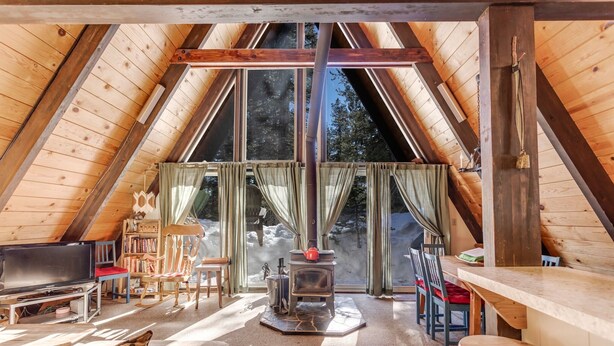 Une pièce mansardée chaleureuse, avec un décor intérieur en bois, une cheminée, une télévision et un coin repas.