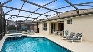 Une piscine entourée de parois en verre, des chaises longues et un espace patio couvert.