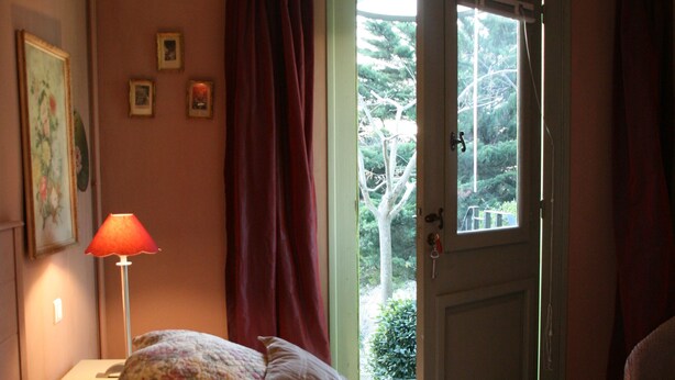 Un dormitorio con una cama, una mesita de noche, una lámpara y una ventana con cortinas.