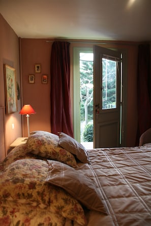 A bedroom with a bed, a nightstand, a lamp, and a window with curtains.