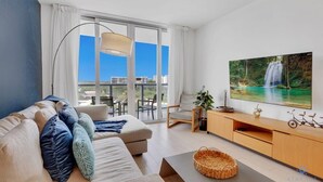 Una sala de estar moderna con un sofá, un televisor y un balcón con vistas a la ciudad.