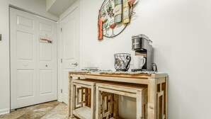 Een hal met een houten salontafel, een koffiezetapparaat en een decoratieve wijnrek.