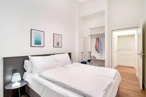 Una habitación de hotel con una cama, una mesita de noche, una lámpara, un armario y un espejo.