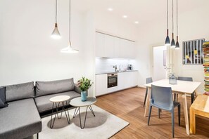 A modern kitchen with white cabinets, a built-in oven, and a dining area with a table and chairs. - 1-Bedroom Apartment 70sqm with a cozy living room(3) (Mitte / Wedding (Berlin))