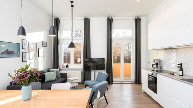 A modern kitchen with a dining area, a TV, and a sofa.