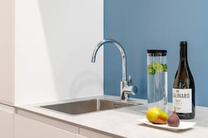 A kitchen with a modern faucet, a wine bottle, and fresh produce on the counter. - 3-Bedroom Apartment (110sqm) with a comfy balcony(5) (Mitte / Wedding (Berlin))