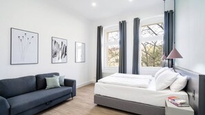 Un dormitorio moderno con una cama, un sofá y dos obras de arte enmarcadas en la pared.