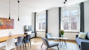 Una sala de estar moderna con una mesa de comedor de madera, sillas, un sofá y un televisor.