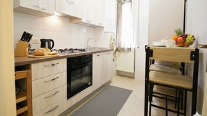 Ett modernt kök med vita skåp, en gasspis, en diskho och ett matbord i trä med stolar.