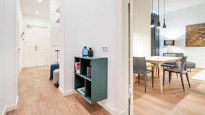 A modern living room with a dining area, a bookshelf, and a door leading to another room.