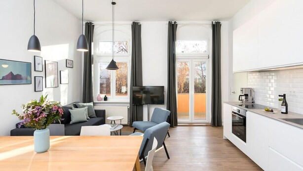 A modern kitchen with a dining area, a TV, and a sofa.