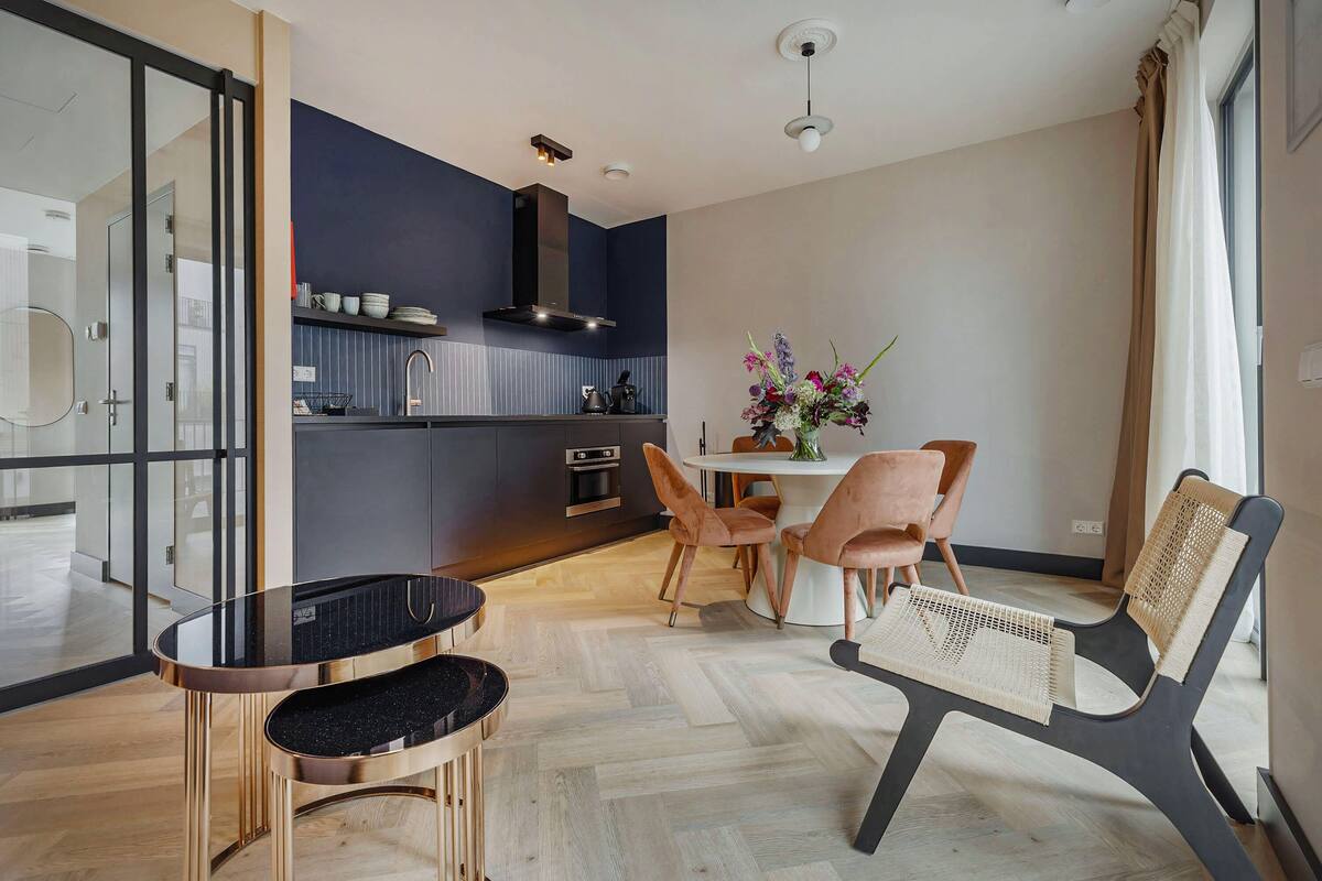 Una cucina moderna con zona pranzo, che include un tavolo rotondo, sedie e un vaso con fiori.