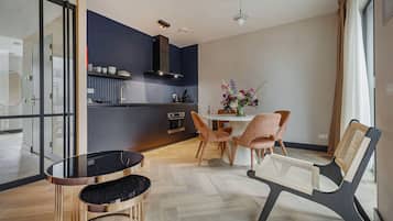 A modern kitchen with a dining area, featuring a round table, chairs, and a vase with flowers.