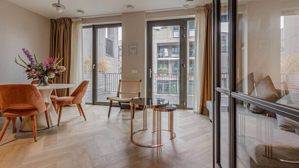 A modern living room with a round table, two chairs, a glass coffee table, and a decorative vase. - Bens The Highdocks (Amsterdam)