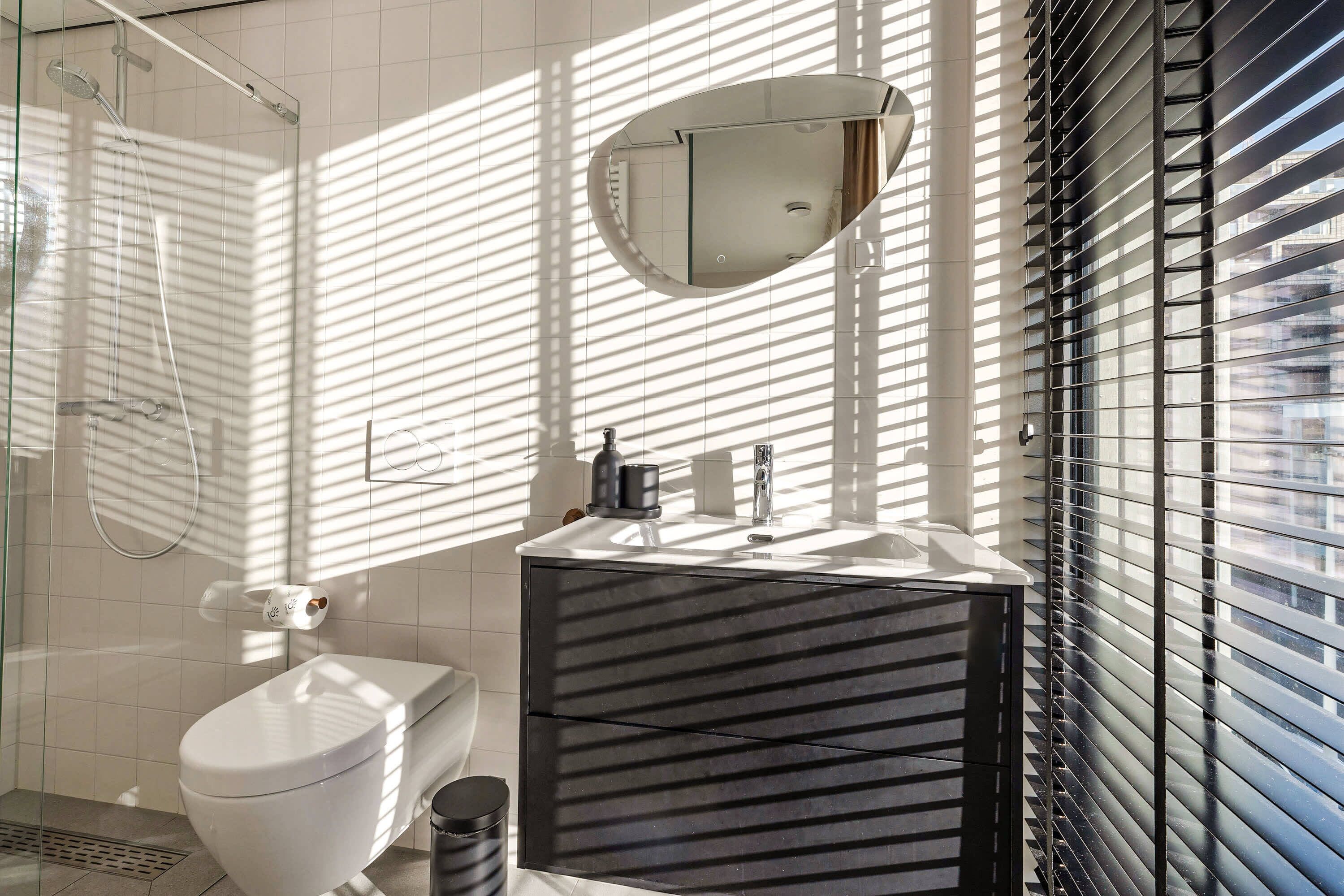 A modern bathroom with a toilet, sink, and shower.