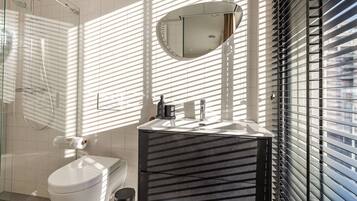 A modern bathroom with a toilet, sink, and shower.