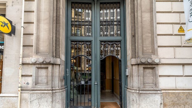Une entrée d’immeuble avec une porte double, un petit seuil et une sonnette bien visible.