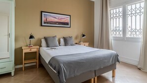 Une chambre à coucher comprenant un lit, deux tables de chevet, une commode, une fenêtre avec vue et un tableau au mur.