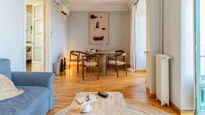 A living room with a sofa, a coffee table, a dining table with chairs, a radiator, and a painting on the wall. - Sagrada Familia view in BCN center (Barcelona)