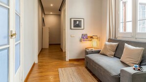A room with a grey sofa, a small rug, a framed picture, and a window with curtains. - Sagrada Familia view in BCN center (Barcelona)