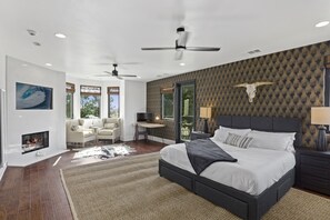 Un dormitorio moderno con una cama grande, una chimenea, un escritorio y un balcón con una decoración de cráneo de vaca.