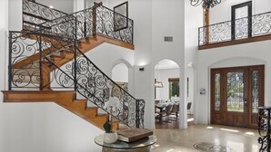 A grand staircase with ornate metal railings and wooden steps, leading to a second floor. - Chateau Vino - French Style Chalet (Temecula)